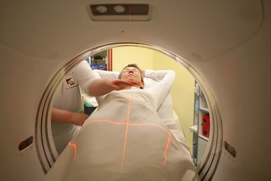 Foto einer Patientin bei einer computertomographie. Die Patientin wird gerade in den Ring des Geräts geschoben